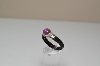 bague en argent ornée d'une pierre violette posée sur du verre transparent