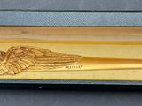 a gold plated pen in a box with wings on it