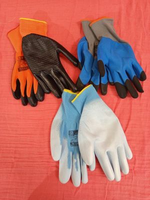 three pairs of gardening gloves laying on a pink surface