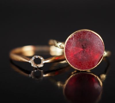 gros plan d'une bague en or avec une pierre rouge