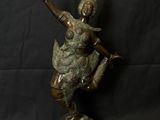 une statue en bronze représentant une femme en train de danser, posée sur un socle