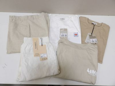 trois paires de pantalons pour homme et un t-shirt posés sur une table