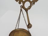 une balance ancienne en laiton à laquelle est suspendue une chaîne à l'arrière