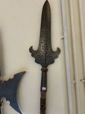 Plusieurs types d'armes sont exposés sur un mur blanc.