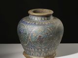 un vase bleu et vert posé sur une table blanche