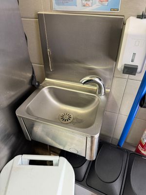 a sink and a trash can in the corner of a bathroom