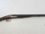 un fusil de chasse avec une crosse en bois posé sur une surface blanche