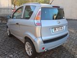 a small silver car parked on a cobblestone street