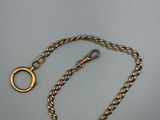 a close up of a gold chain with a ring on it