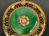 une image représentant un pendentif vert et doré orné d'une fleur