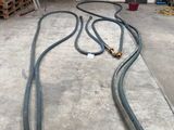 two hoses that are sitting on the floor in front of some barrels