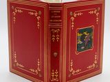 Le livre est rouge, avec des bordures dorées et une illustration sur la couverture.