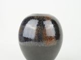 a black and brown vase sitting on a white surface