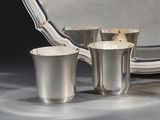 trois tasses en argent et un plat en argent posés sur une table