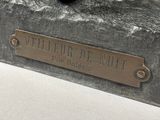 statue of a dog laying down on a table with a plaque on it ' s side