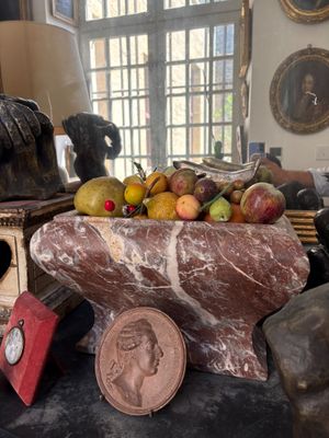 a bowl of fruit on a table next to a statue of a man