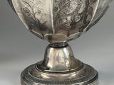 an antique silver vase with a bird design on the top of it