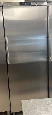 three stainless steel refrigerators in a kitchen with a table