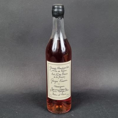une bouteille d'alcool posée sur une table, devant un fond gris