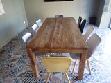 a wooden table with chairs and a painting on the wall