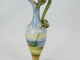 a blue and yellow vase with a green handle on it