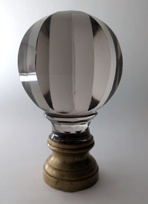 une boule de verre posée sur un socle en bois, sur fond blanc