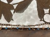 a metal sculpture of a bird on a branch with leaves on it
