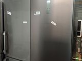 un grand réfrigérateur argenté dans une pièce où il y a plein d'aimants collés dessus