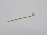 une broche composée d'une perle et d'or sur fond blanc