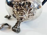 a silver tea pot with a handle on a white table