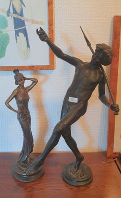 une statue représentant un homme tenant une lance et une femme tenant une épée