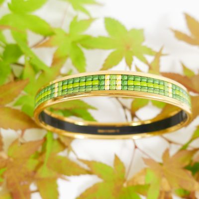 a close up of a bangle with green and yellow squares on it