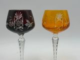 two wine glasses with different colored designs on them sitting next to each other