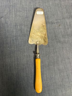 une spatule à manche jaune en bois posée sur une surface grise