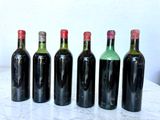 six bottles of wine are lined up on a marble table