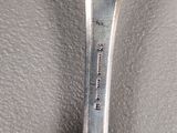 silver spoon with a spoon handle on it sitting on top of a leather surface