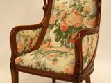 une chaise dont le dossier est recouvert d'un tissu à motifs floraux et dont la structure est en bois