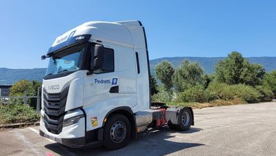 un camion blanc garé sur un parking, avec les montagnes en arrière-plan