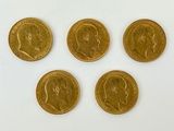 quatre pièces d'or de tailles et de formes différentes sur une surface blanche