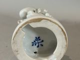 a small white vase with a blue flower on it