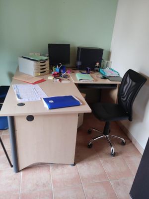 a desk with two computers and a chair in the corner