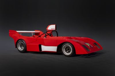 La voiture de course rouge et blanche est garée sur une surface noire.