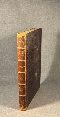an old book sitting on top of a table with a gray background