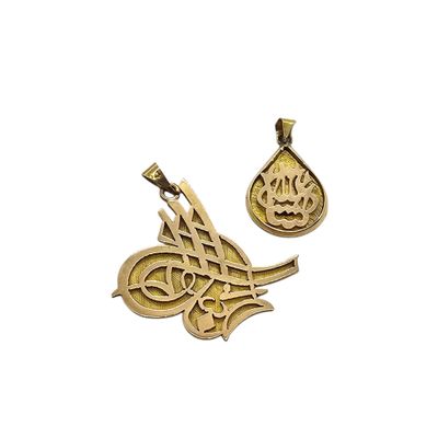 a close up of two gold pendants with arabic writing on them