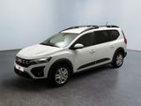 La voiture blanche est garée dans une pièce au sol gris.