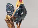 a figurine of a rooster standing on a tree branch