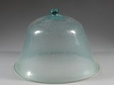 a glass dome with a green lid on a white table