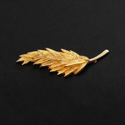 a gold leaf broochle on a black background