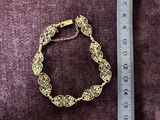 a close up of a gold bracelet on a purple cloth next to a ruler