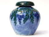 a blue vase with a green lid sitting on a white surface